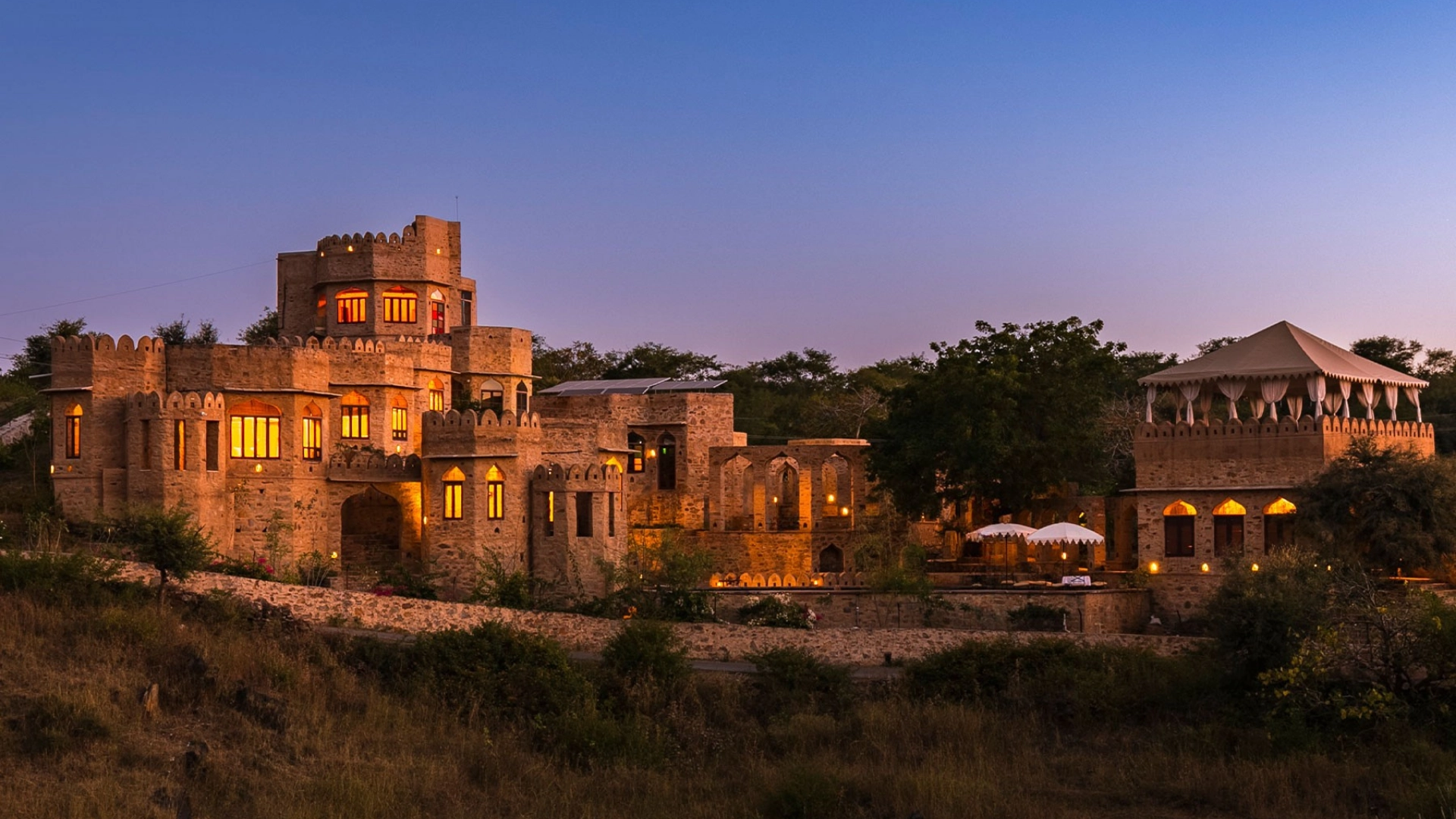 Raht Manmatha private sandstone fort estate lit at dusk above Badi Lake, Udaipur, Rajasthan